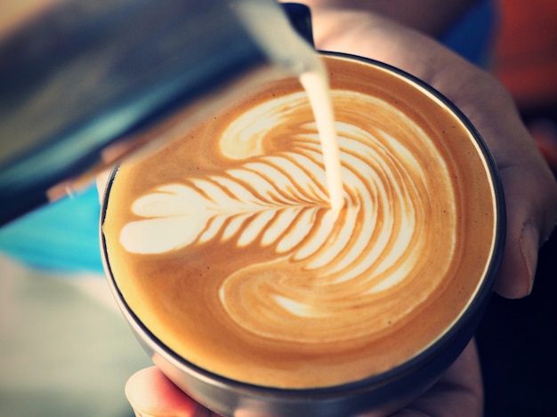 Person pouring milk into a cup of coffee