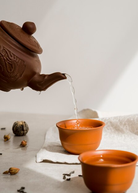 Person pouring tea from clay teapot