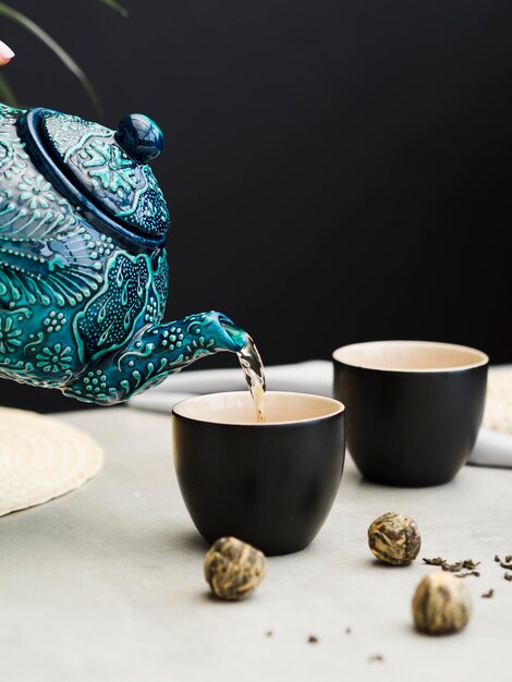 Person pouring tea from teapot in cup