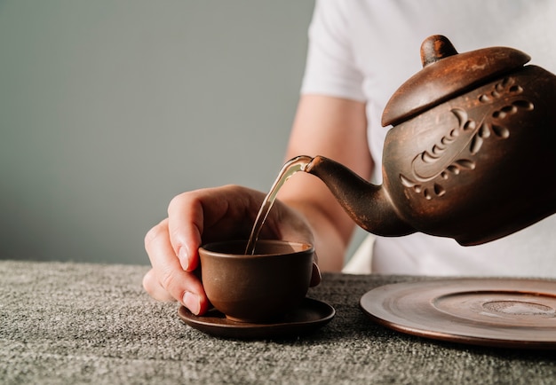 Person pouring warm tea in a cup