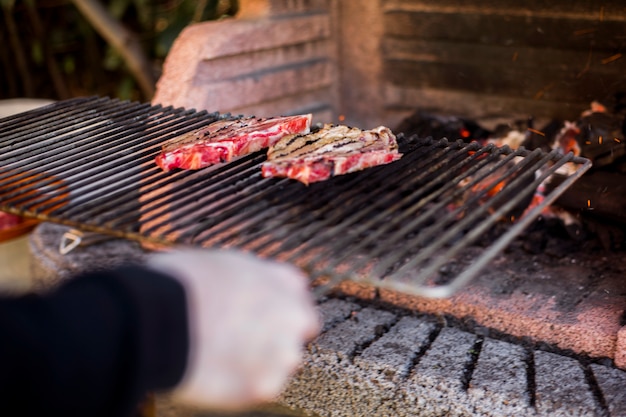 Free Photo a person preparing grilled beef on barbecue