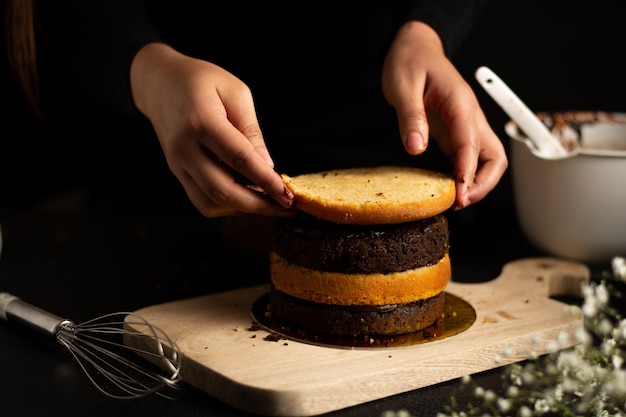 Person preparing a small cake with chocolate and vanilla layers