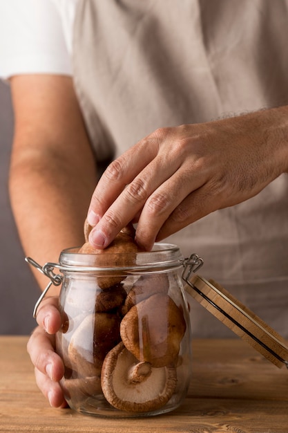 Person putting mushrooms in glass jar