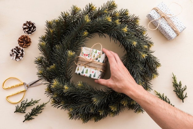 Free Photo person putting small gift box in christmas wreath 