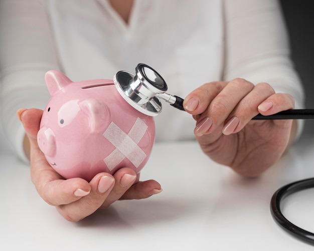 Free Photo person putting a stethoscope on a piggy bank