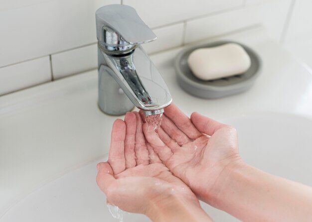 Person rinsing hands before washing with soap