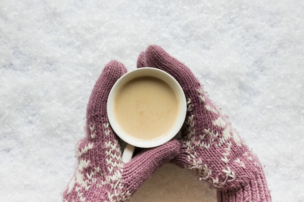 Free Photo person's hand in cozy glove holding coffee cup on snowy land