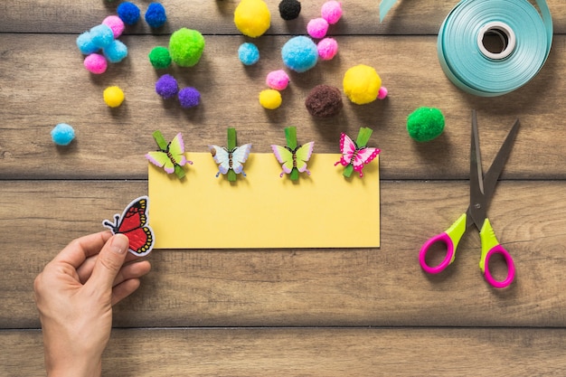 A person's hand holding butterfly sticker making yellow card