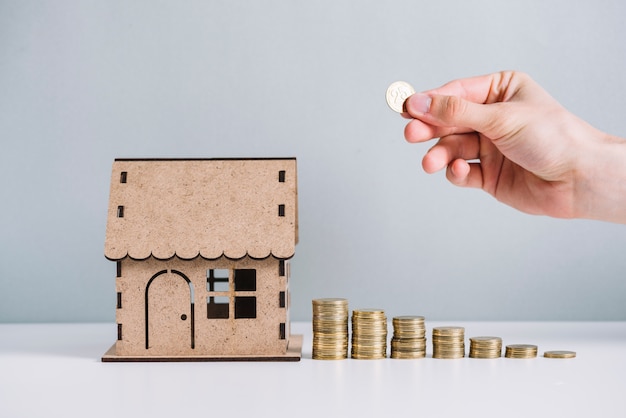 Free photo a person's hand stacking coins near house model