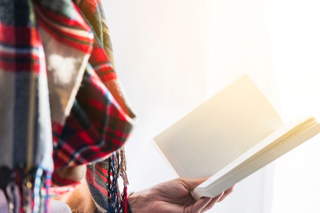 Person in scarf holding book