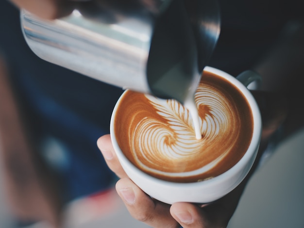 Free photo person serving a cup of coffee with a metal jug