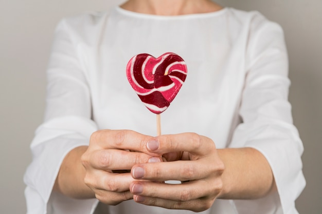 Person showing lollipop in form of heart