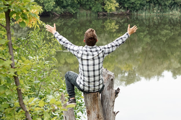 Person sitting on a tree with hands wide-open