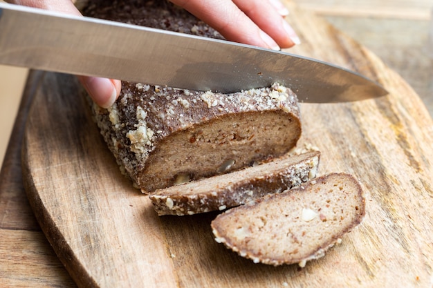 Free photo person slicing raw vegan bread with a knife