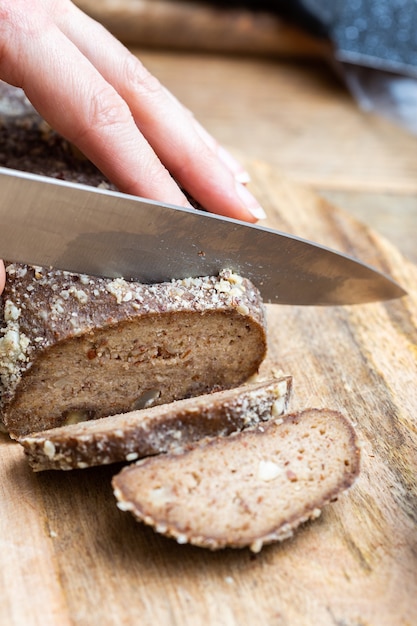 Person slicing raw vegan bread with a knife