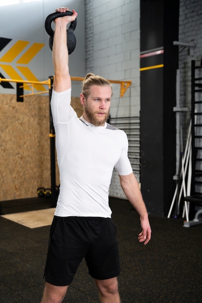 Free photo person in sport gym using kettlebells