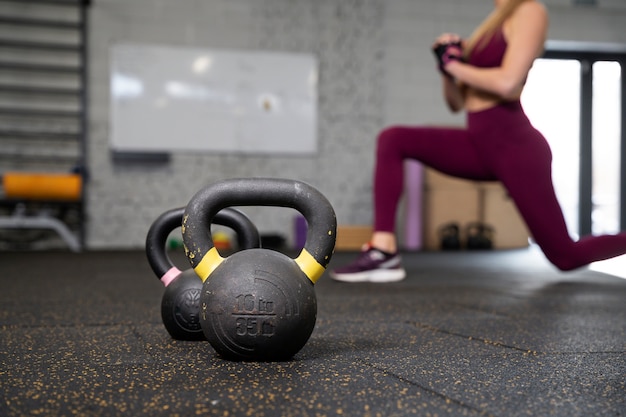 Free photo person in sport gym using kettlebells