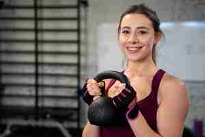 Free photo person in sport gym using kettlebells