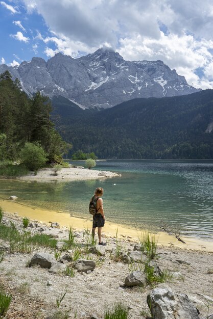 Person standing on beach of the Eibsee lake in Germany surrounded by the mountains