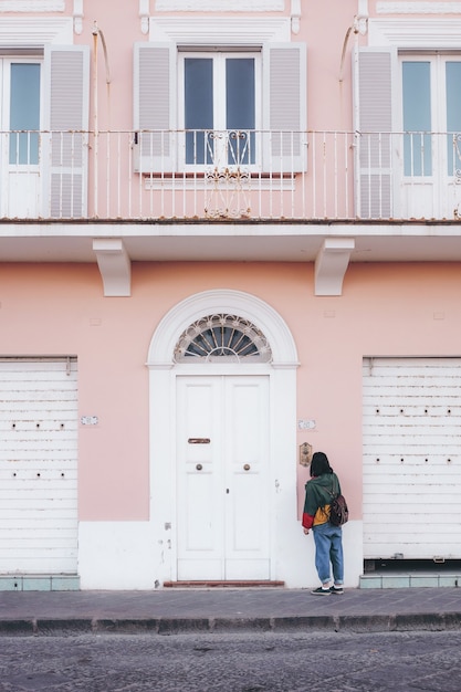 Free photo person standing in front of pink and white painted building