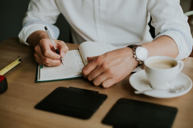 Person taking notes in a notebook while working from home