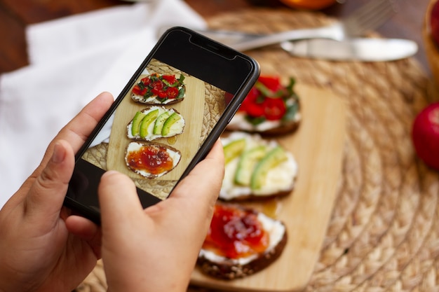 Free Photo person taking photo of assortment of sandwiches with smartphone