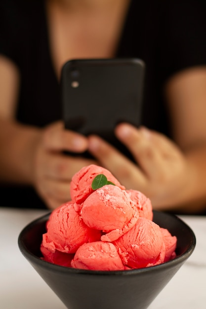 Free photo person taking photo of ice cream scoops in bowl with smartphone