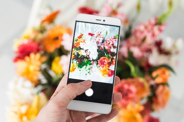 Free photo a person taking photograph of flower bouquet with smartphone