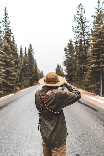 Person taking photograph of road between trees