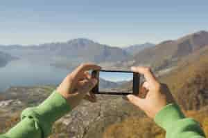 Free photo person taking a picture of the maggiore alpine lake and mountains in switzerland