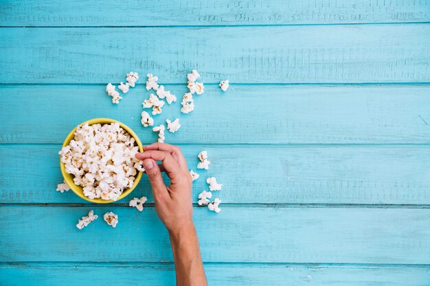 Person taking popcorn from bowl