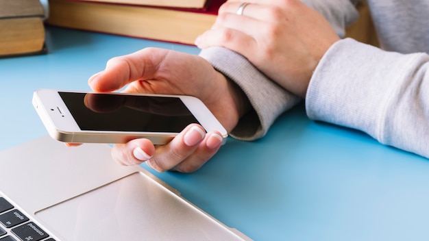 Person touching mobile phone on a desk