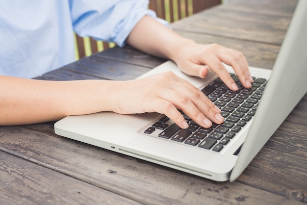 Person typing on a laptop on a wooden table