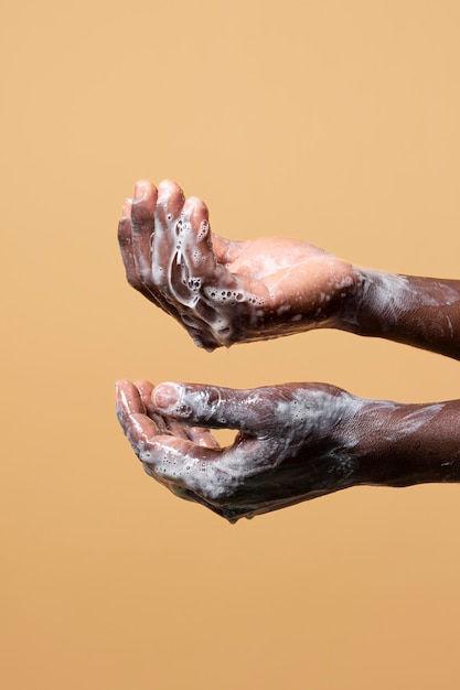 Person washing hands with soap isolated on orange