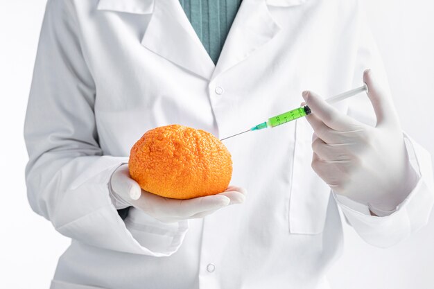 Person wearing gloves injecting an orange