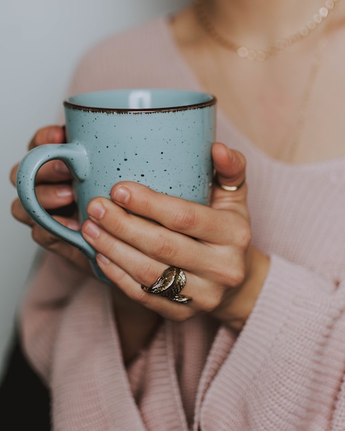 Free photo person wearing a pink sweater holding a blue mug