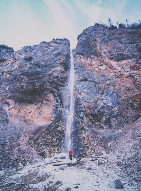 Person wearing red jacket standing near waterfalls