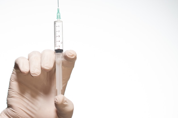 Person wearing a surgical glove holding a syringe isolated on a white background