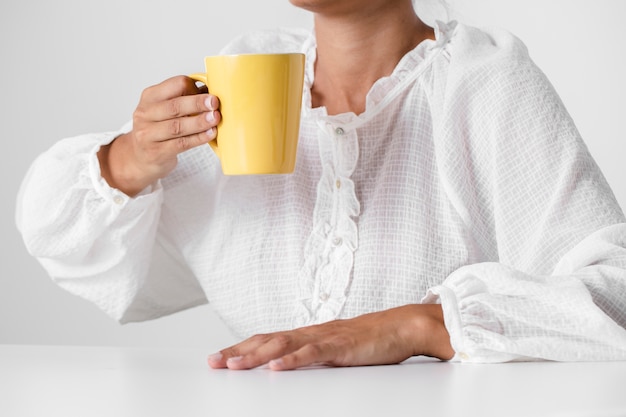 Free Photo person in white shirt holding a cup