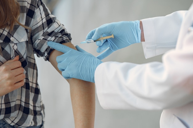 Person in a white uniform holding a syringe in her hands