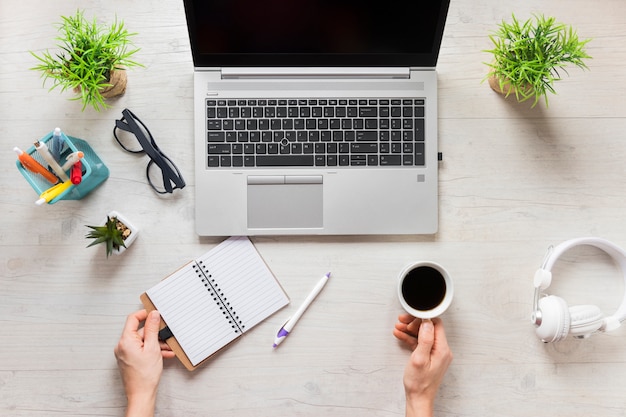 Free photo a person with diary and coffee cup on wooden desk with an open laptop