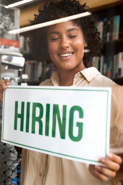 Person with hiring sign by the window