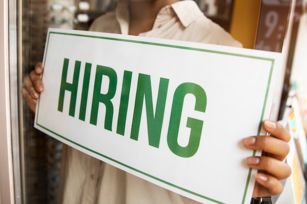 Person with hiring sign by the window