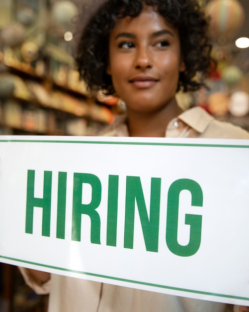 Person with hiring sign by the window