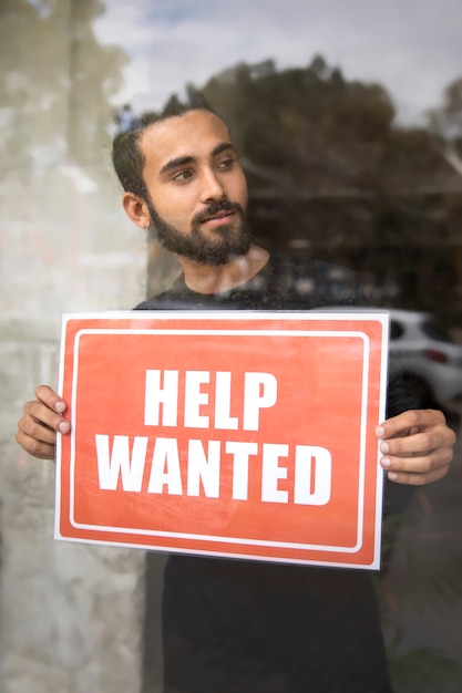 Person with hiring sign by the window