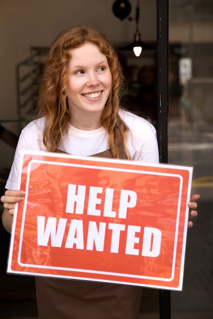 Person with hiring sign by the window