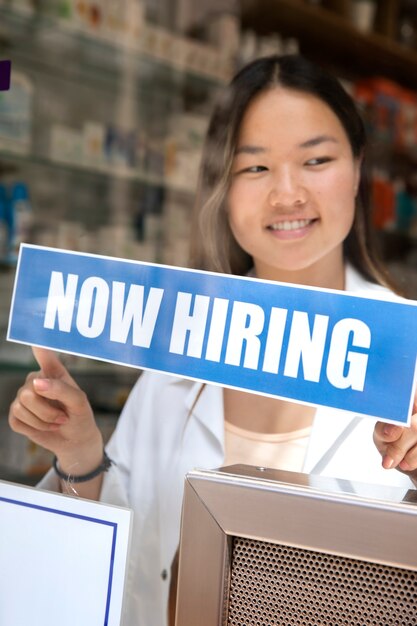 Person with hiring sign by the window