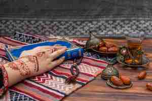 Free photo person with mehndi holding quran book near tea