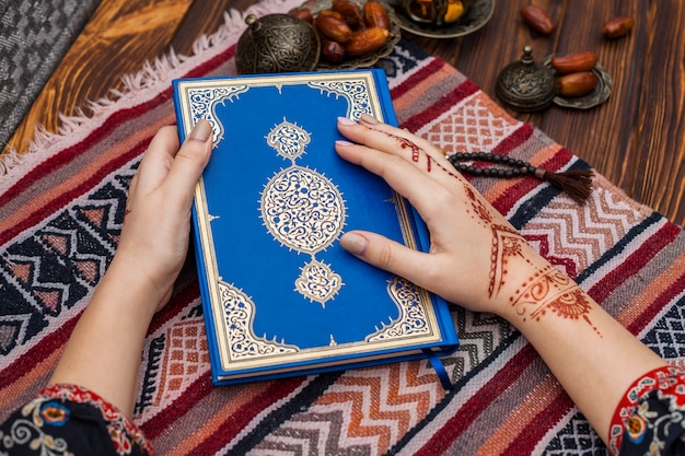 Free photo person with mehndi holding quran near dates fruit