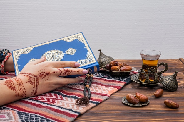 Free photo person with mehndi holding quran near tea glass